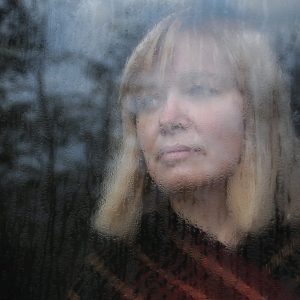 Sad woman behind rainy glass
